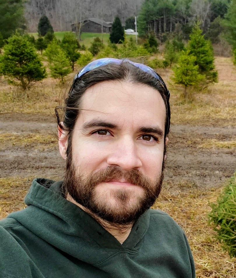 A headshot of Jay Tourigny. He has brown hair and a brown beard.